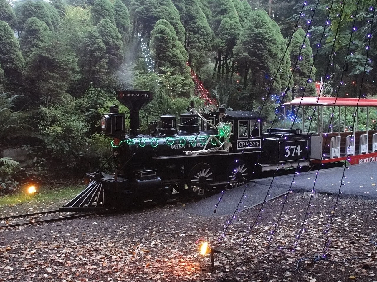 Stanley Park miniature locomotive 374 and passenger carriages beside forest